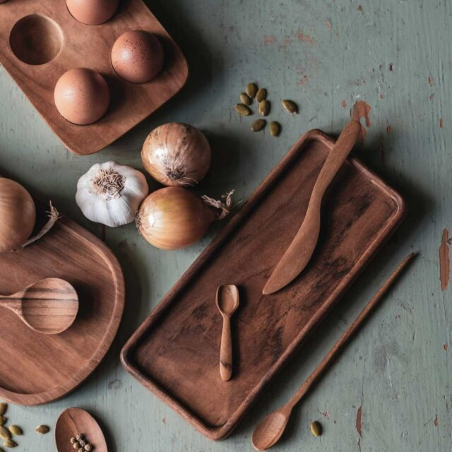Puinen käsityönä valmistettu voiveitsi ja lusikoita ja puuastioita asetelmassa keittiönpöydällä