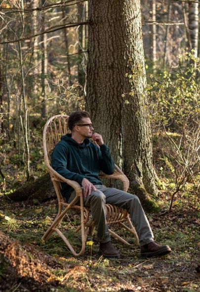 Mies istuu korkeassa lumikenkätuolissa metsässä